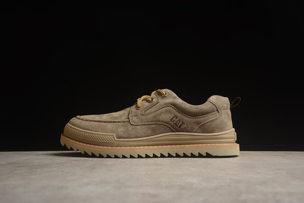 Side view of taupe-brown CAT Tramp Hike Low shoes against a dark background