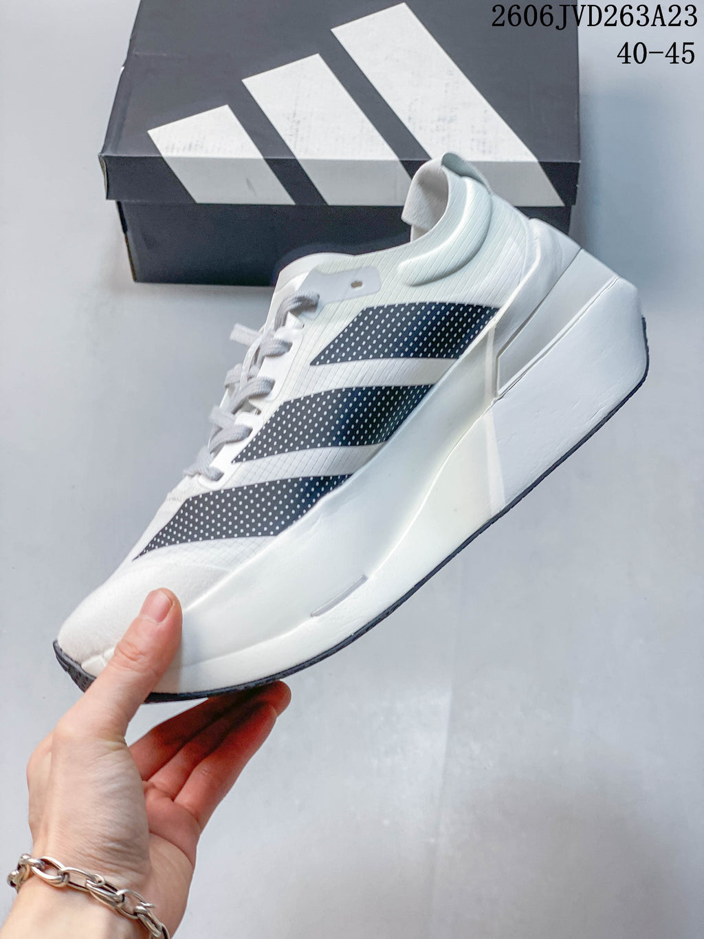 Side view of a white Adidas shoe with dark three-stripe detailing and a sculpted sole; image overlay states sizes 40–45.