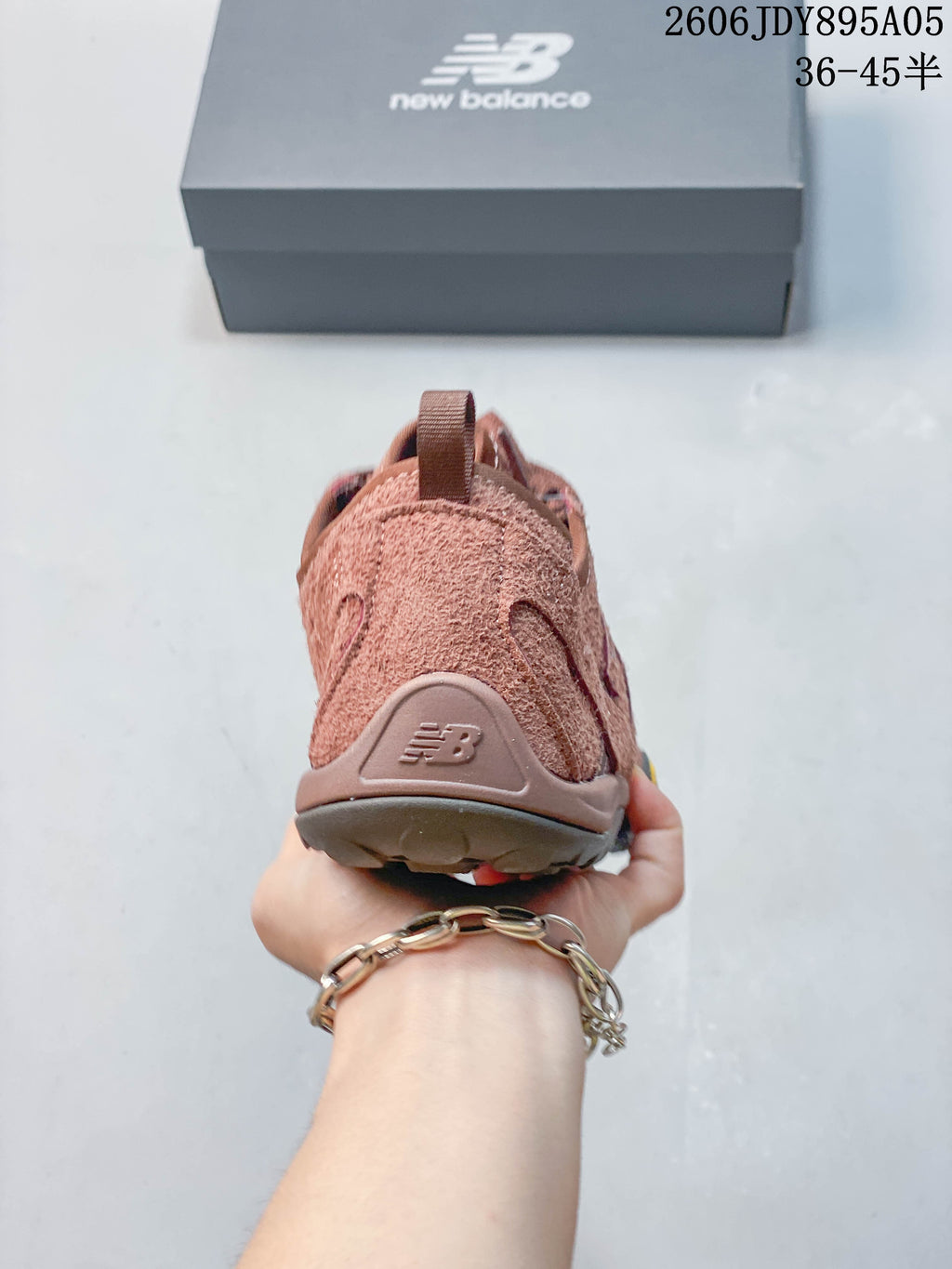 Rear view of a dusty rose New Balance sneaker showing the heel panel and pull loop