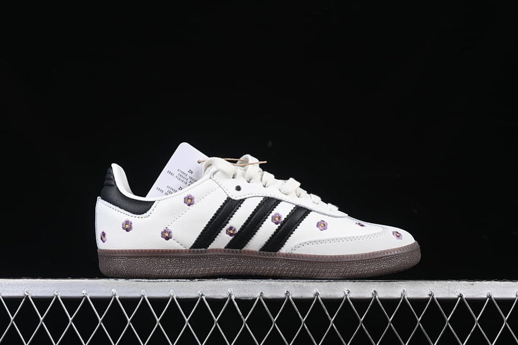 Side profile showing white upper, black stripes, floral embroidery, and dark brown outsole