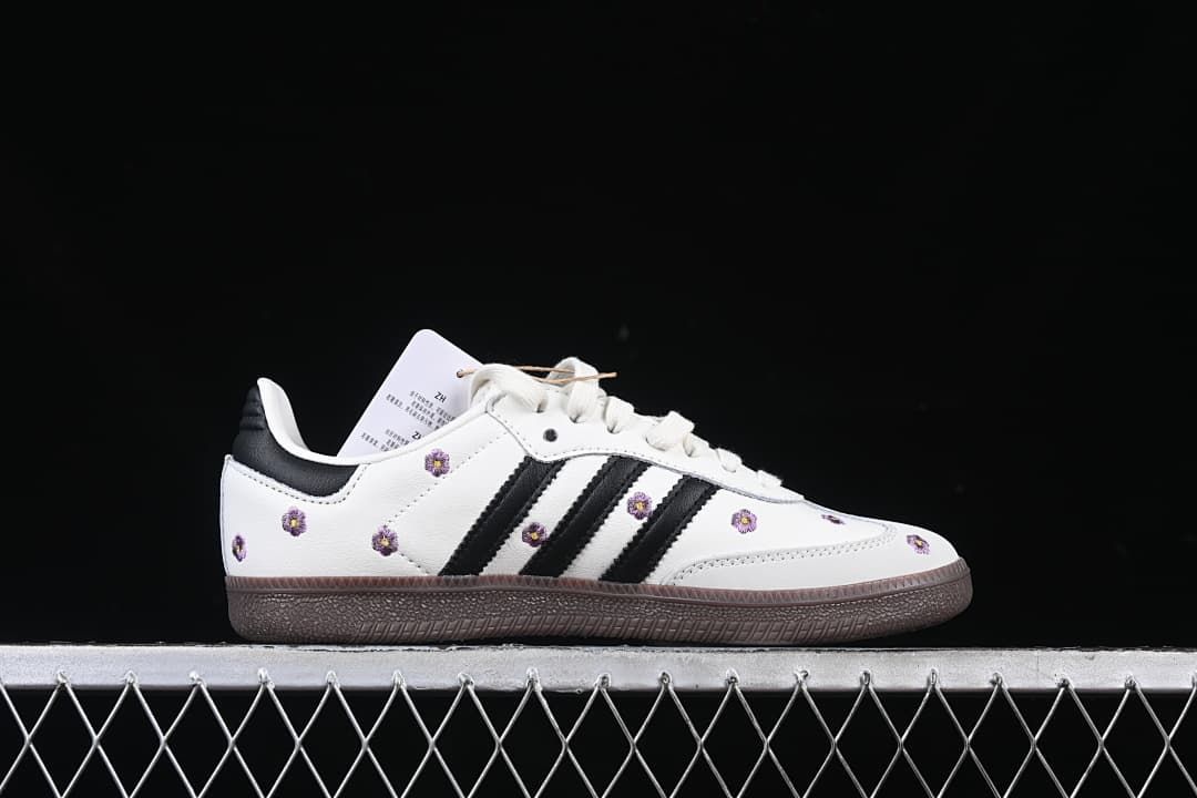Side profile showing white upper, black stripes, floral embroidery, and dark brown outsole