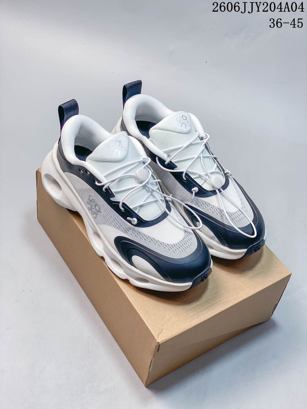 Pair of white and navy On Cloudtilt sneakers on a box