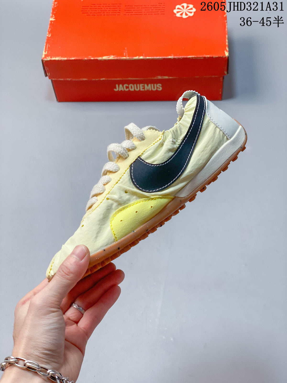 Side view of a pale yellow Nike x Jacquemus sneaker with dark side accent and gum-colored sole
