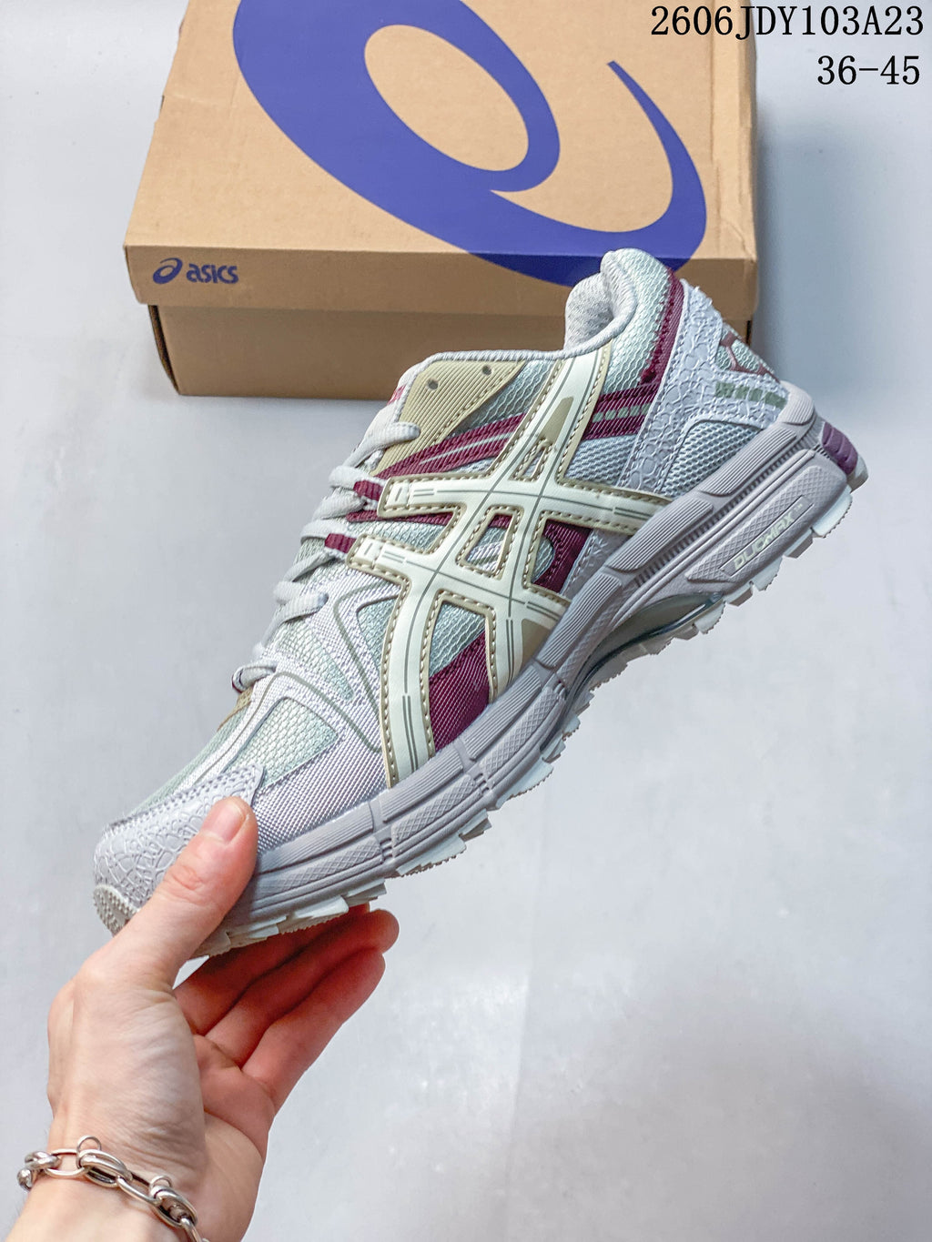 Side profile of the ASICS Gel-Kahana 8 with layered overlays and pale gray-white, cream, and burgundy details.