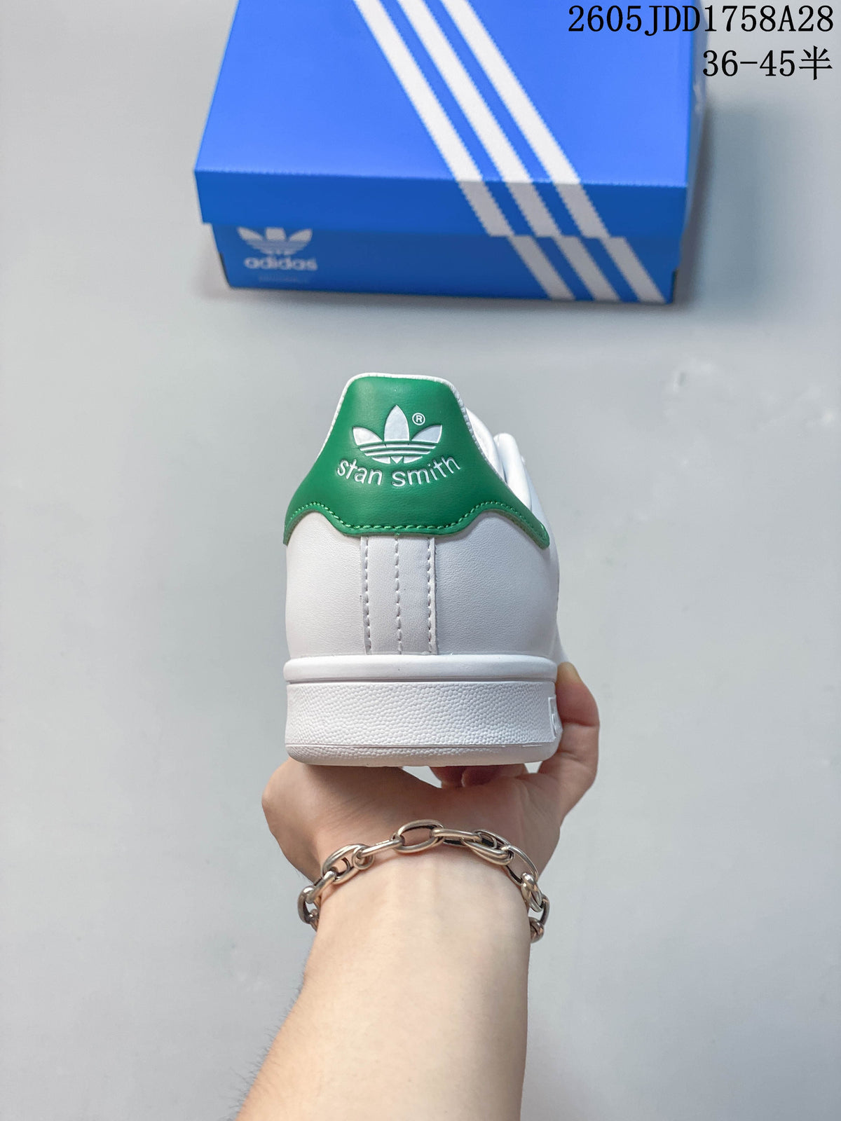 Rear view of a white sneaker with a green Stan Smith heel tab