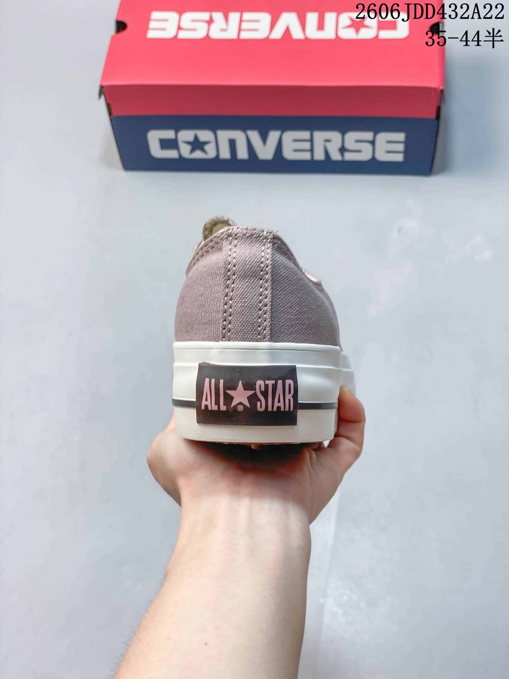 Rear view of a taupe Converse All Star sneaker with a branded heel patch