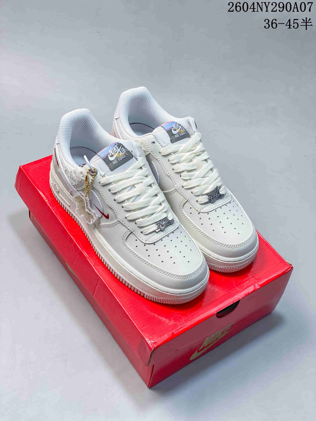 White low-top sneakers with decorative details shown on a red box.