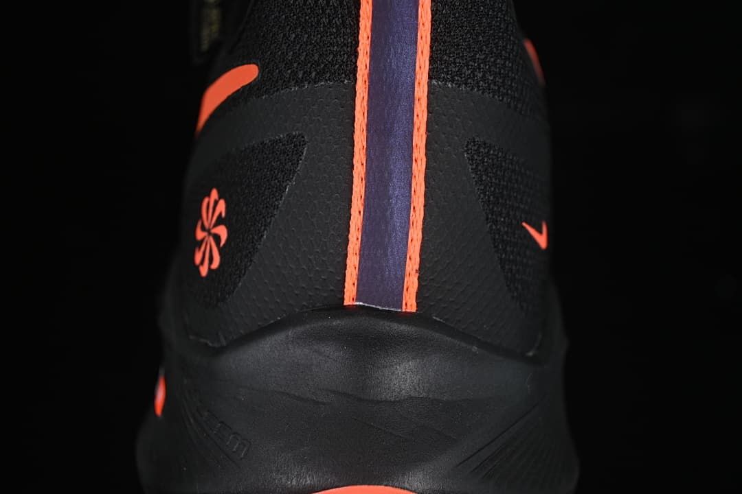 Rear view of the black shoe with coral heel details and a central stripe.
