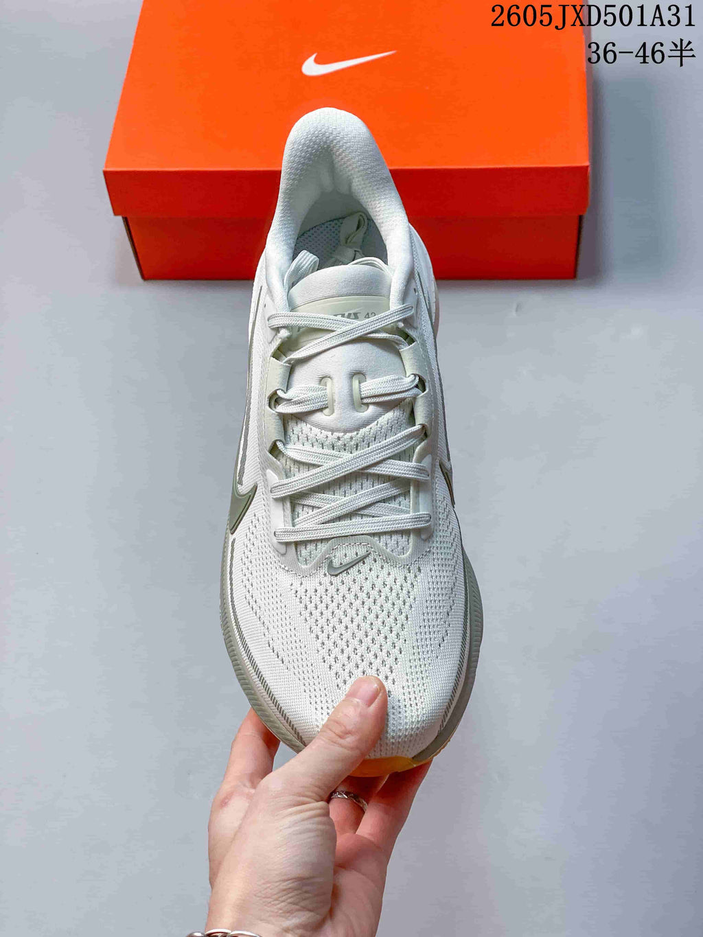 Top view of the lace-up running shoe with a perforated-looking upper and orange box in the background