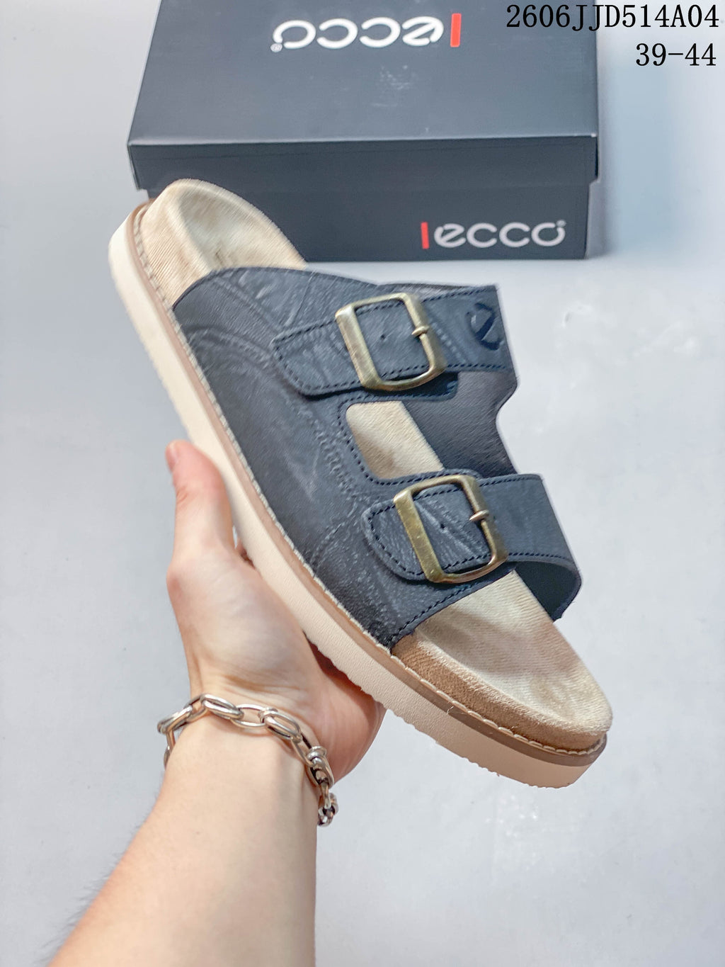 Angled view of the blue two-buckle slide sandal with light-colored footbed and sole; image overlay shows style code 2606JJD514A04 and sizes 39–44.
