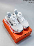 Pair of white Nike Vomero Premium running shoes with pink midsole accents, shown on an orange shoe box.