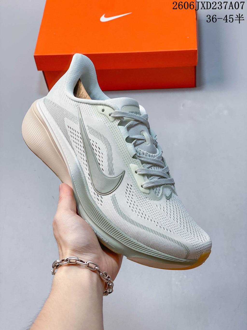 Angled side view of a Nike Pegasus 42 running shoe with light gray upper and muted green accents.