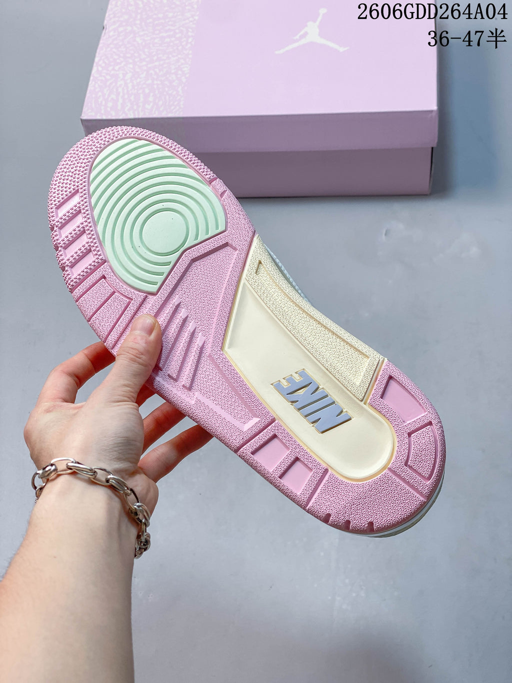 Underside of the sneaker showing a pink outsole and pale green traction section.