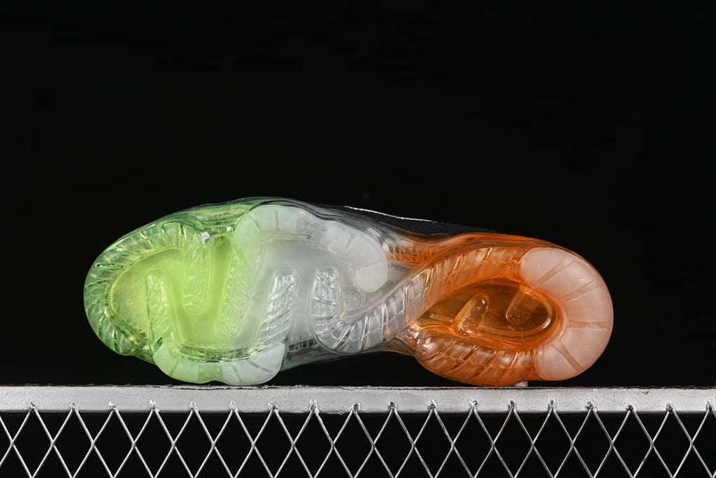 Underside view of the transparent sole with green, clear, and orange sections.