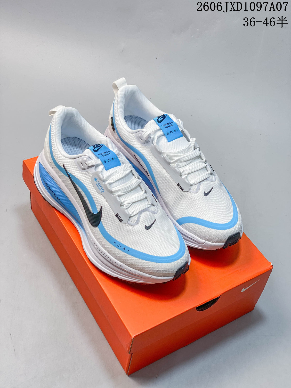 Pair of white and blue Nike Vomero 18 shoes viewed from above on an orange box