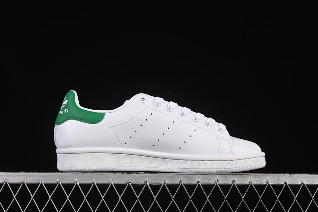 Side profile of the white sneaker with perforated detailing and green heel tab