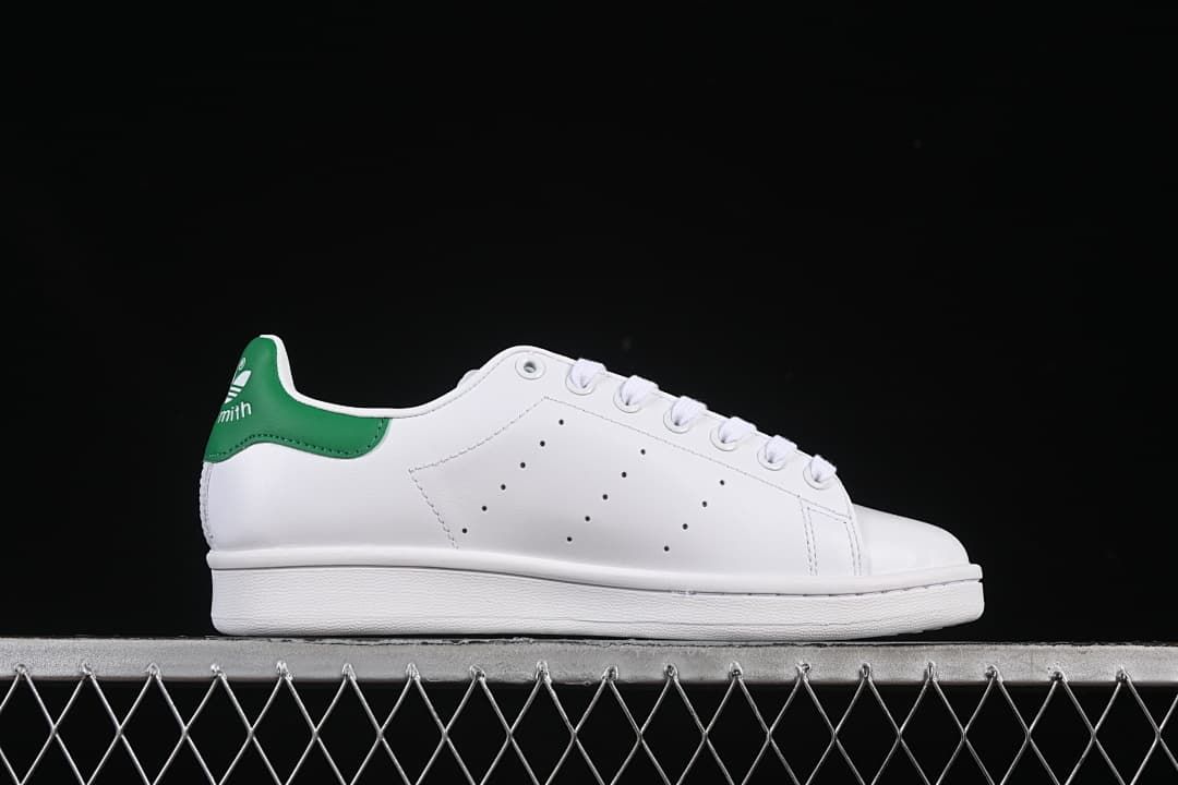 Side profile of the white sneaker with perforated detailing and green heel tab