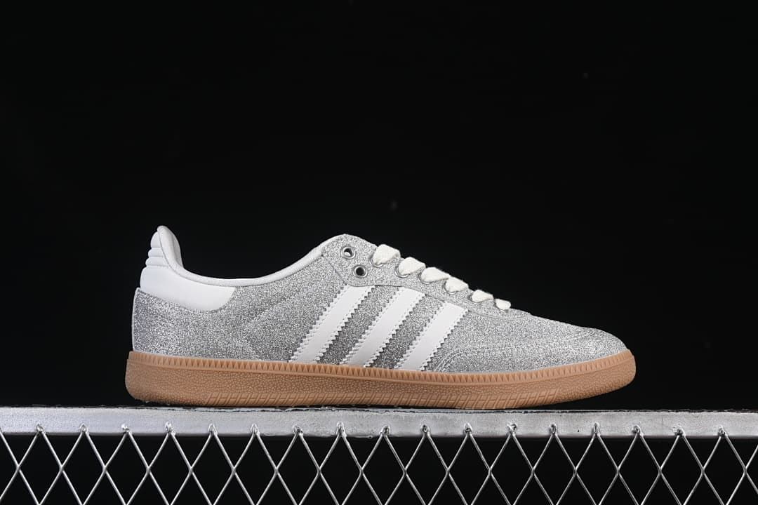Side profile of the silver glitter-effect Samba OG with white stripes and gum sole.