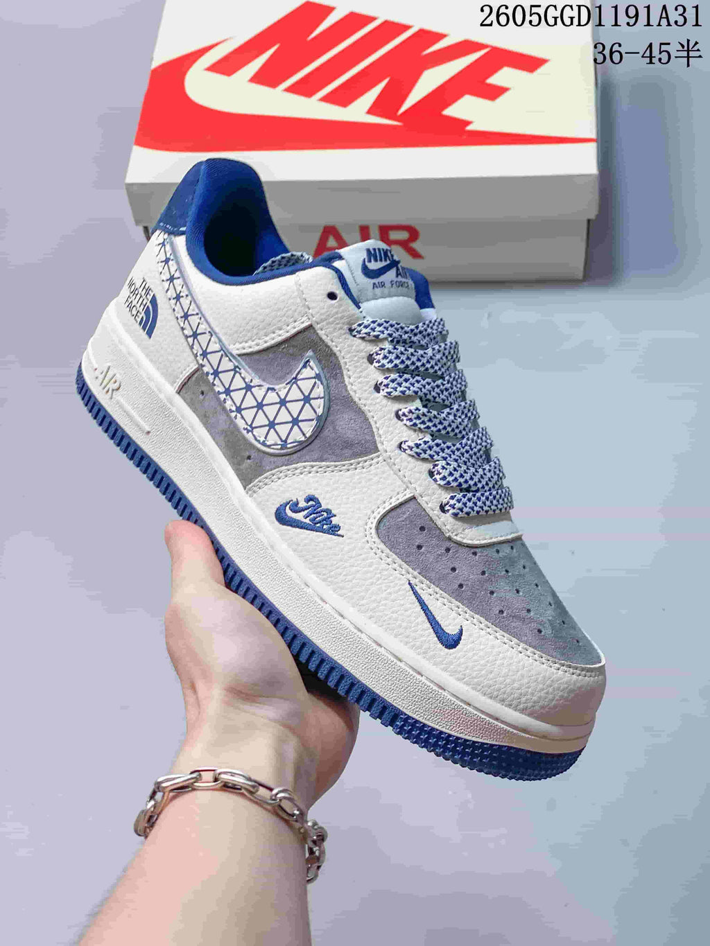 Angled side view of the sneaker showing its grey and off-white panels, patterned laces and blue outsole.