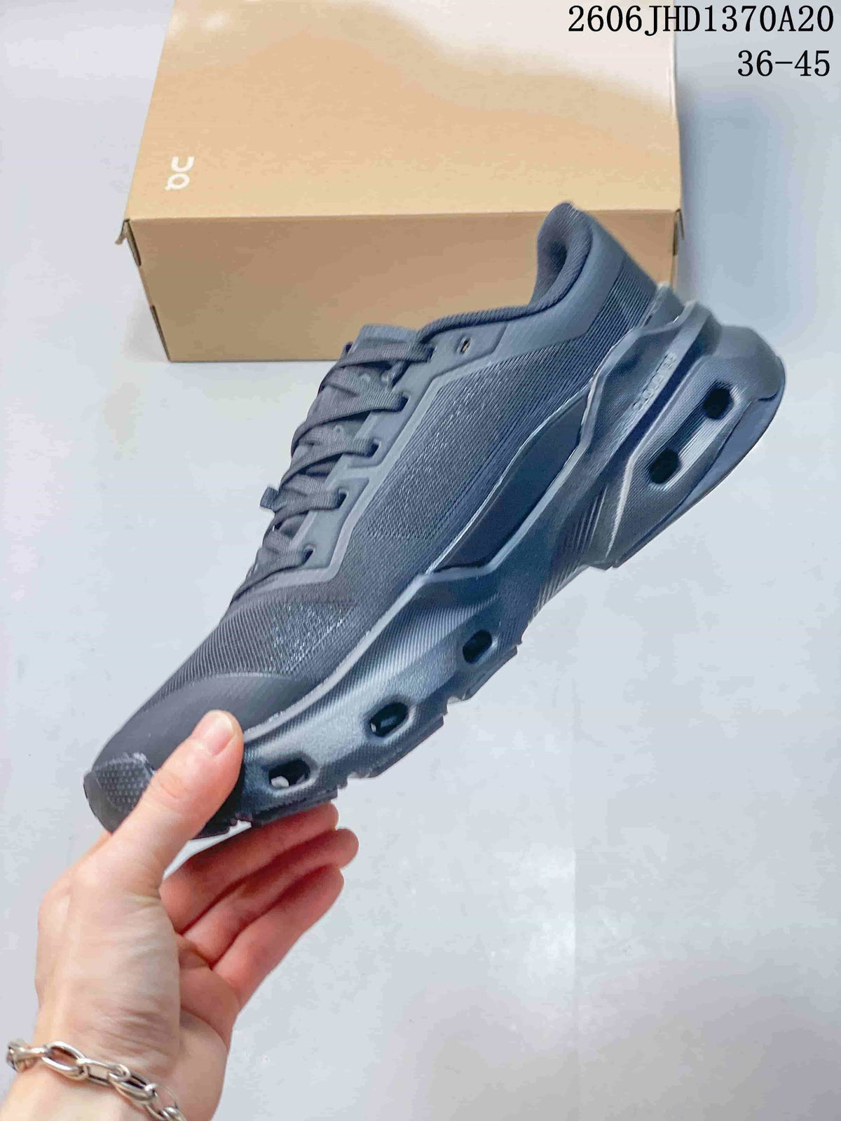 Side profile of a charcoal gray lace-up sneaker with visible openings in the sole.