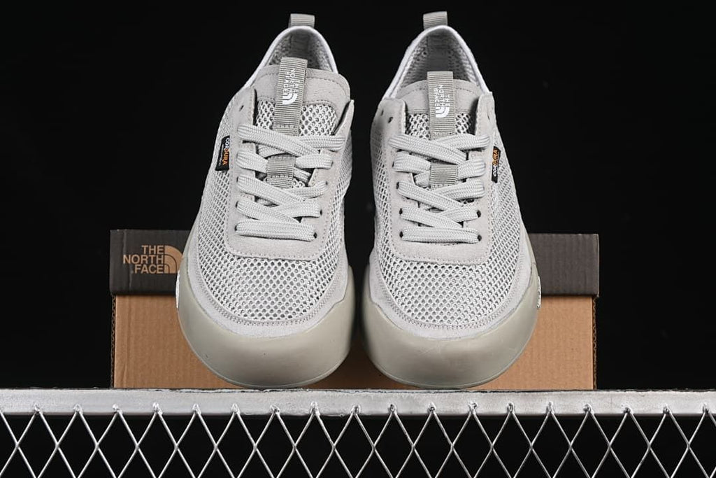 Front view of the pair of grey lace-up sneakers resting on the box.