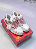 Pair of white and red low-top sneakers with patterned laces and decorative accessories on a red shoe box