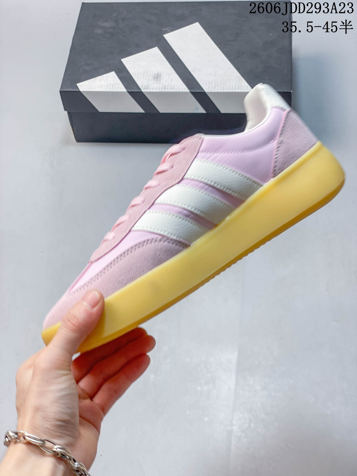 Side view of a pink and white sneaker with three stripes and a gum-colored sole