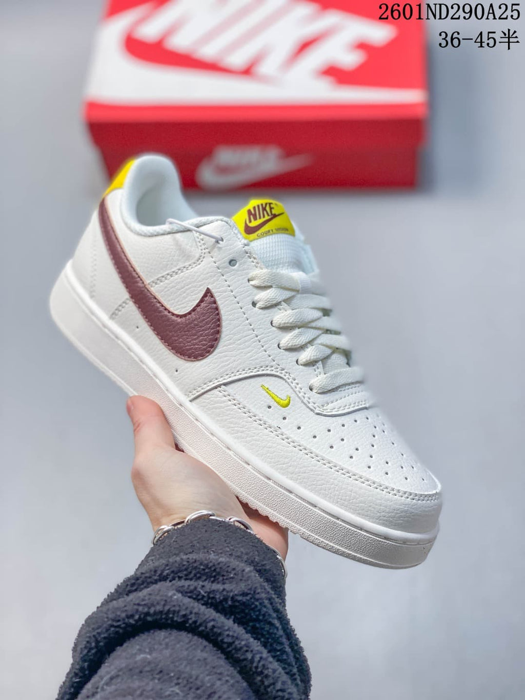 White low-top sneaker with burgundy accents and yellow tongue label