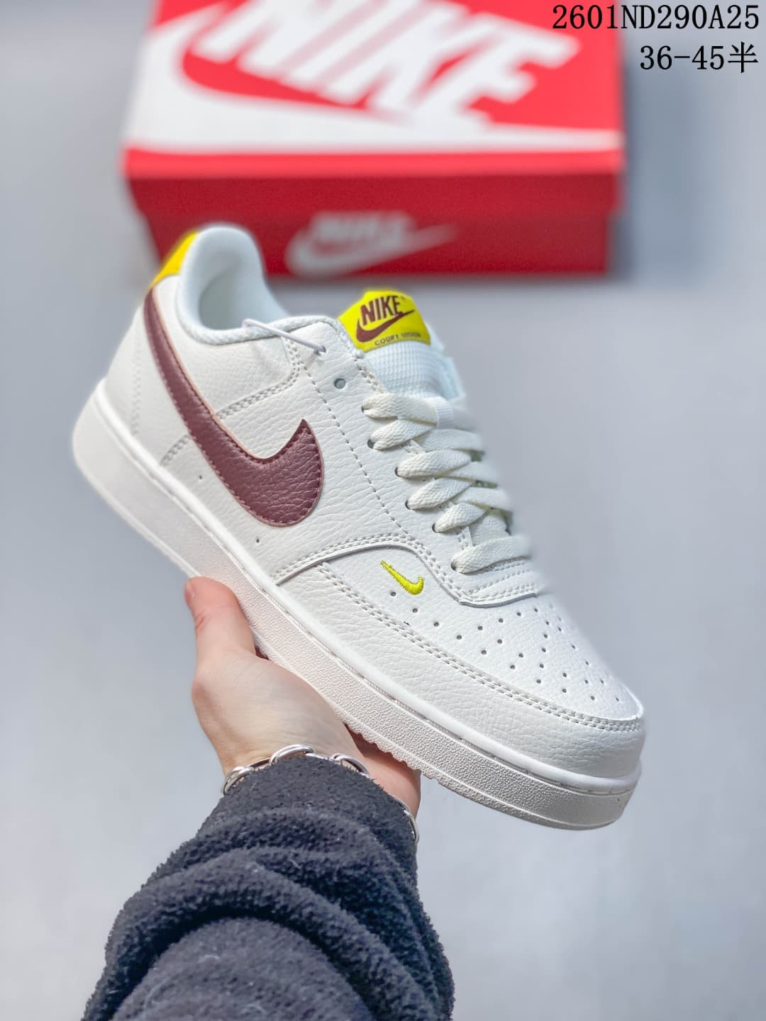 White low-top sneaker with burgundy accents and yellow tongue label