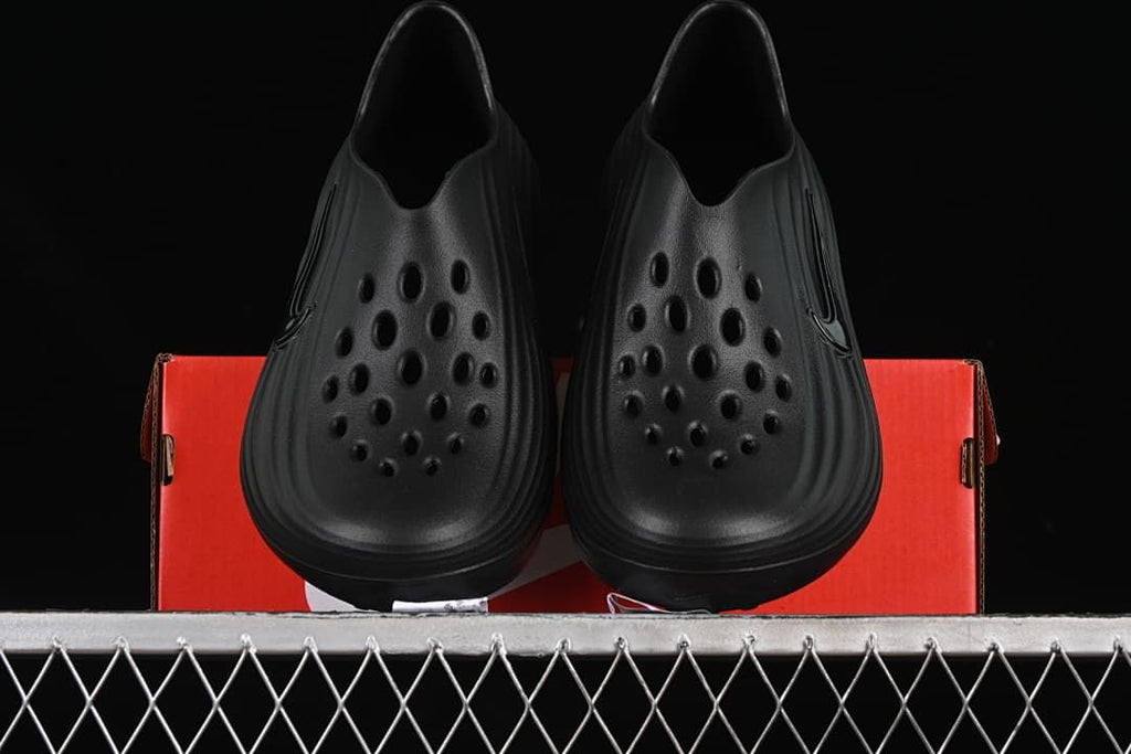 Pair of black slides shown from above on a red shoe box