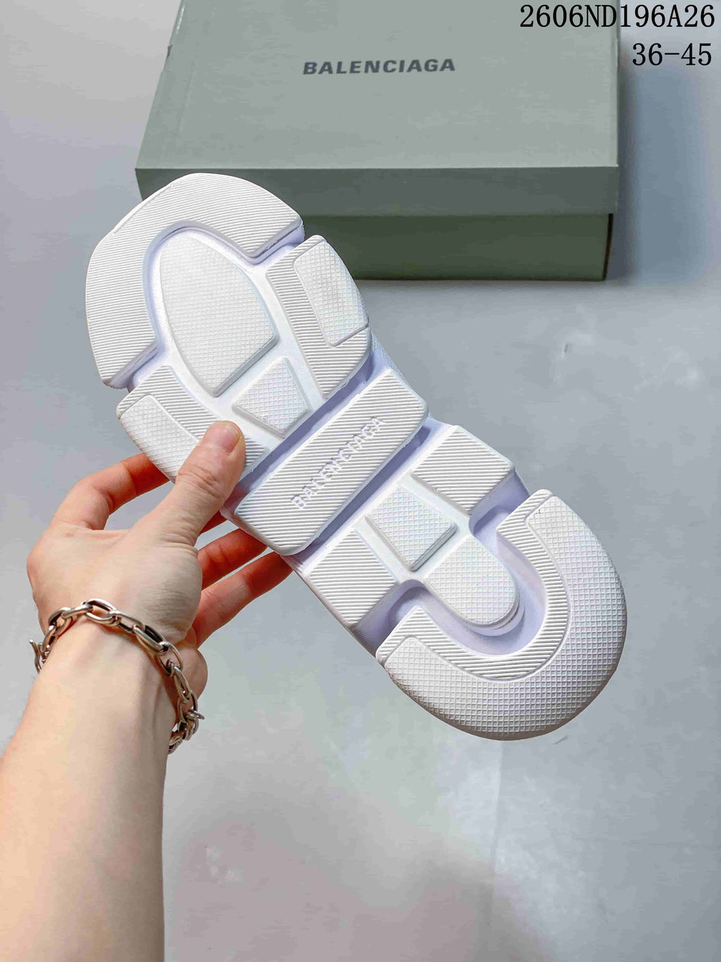 Underside of a white sneaker showing the segmented sole pattern.
