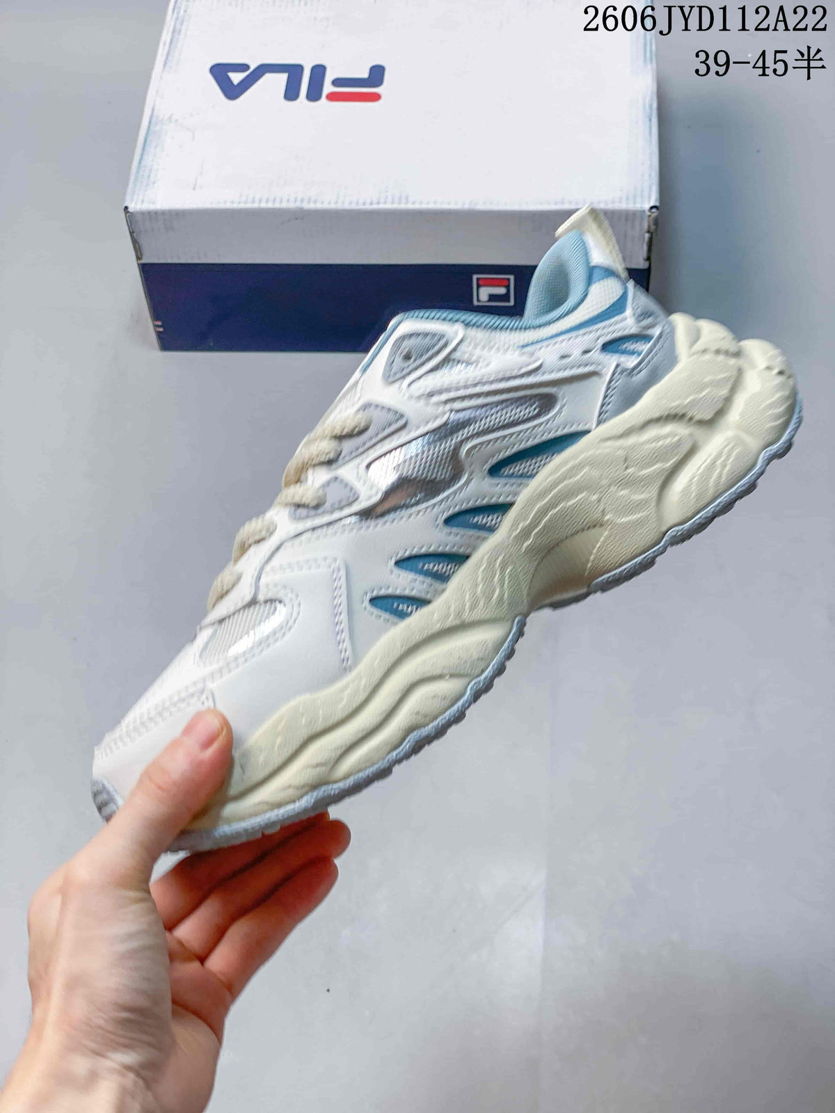 Side profile of a white FILA sneaker with light blue accents and a chunky sole.