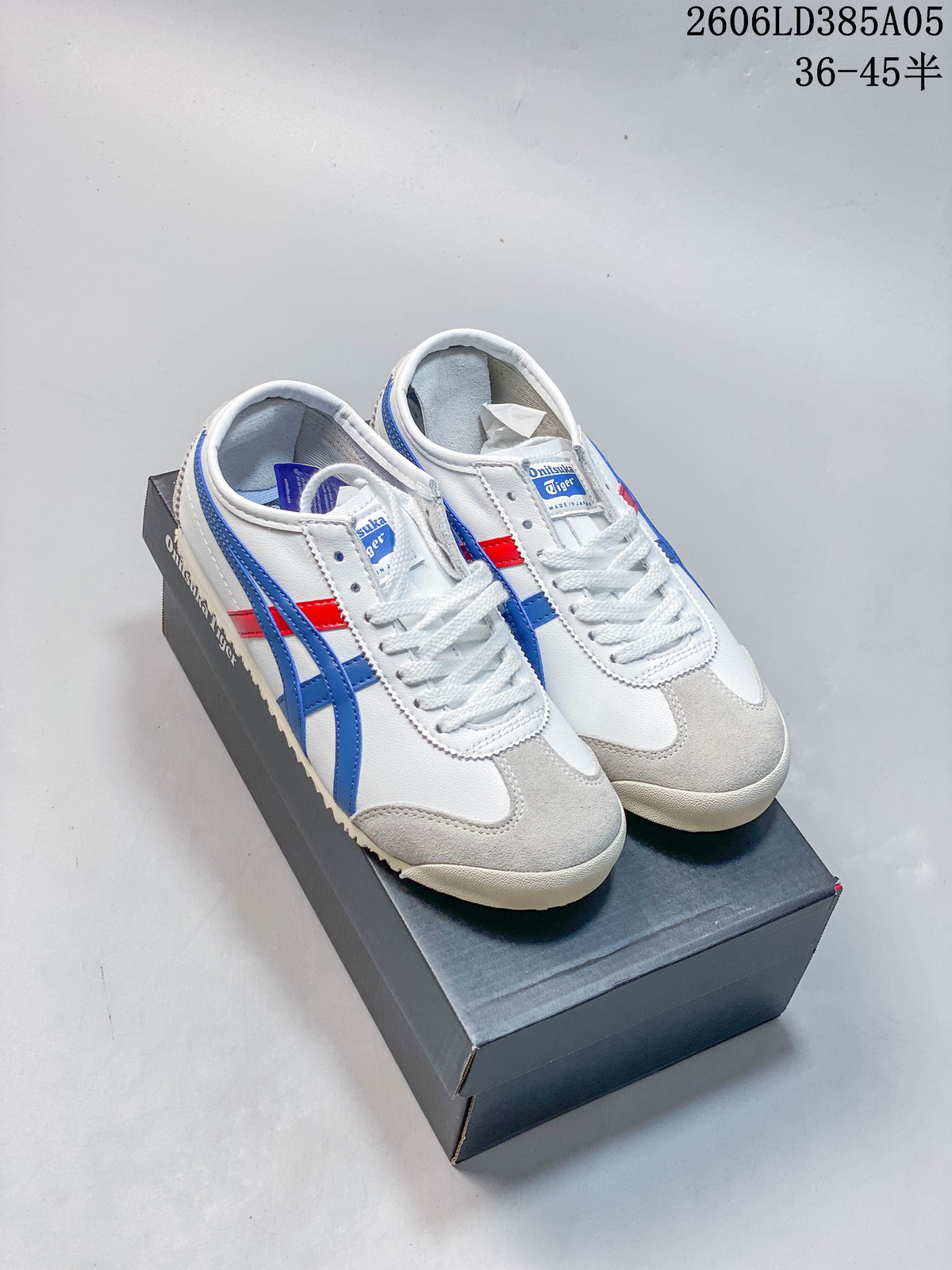 White Onitsuka Tiger Mexico 66 Deluxe sneakers with blue stripes, red accents and grey toe overlays, shown on a shoebox.