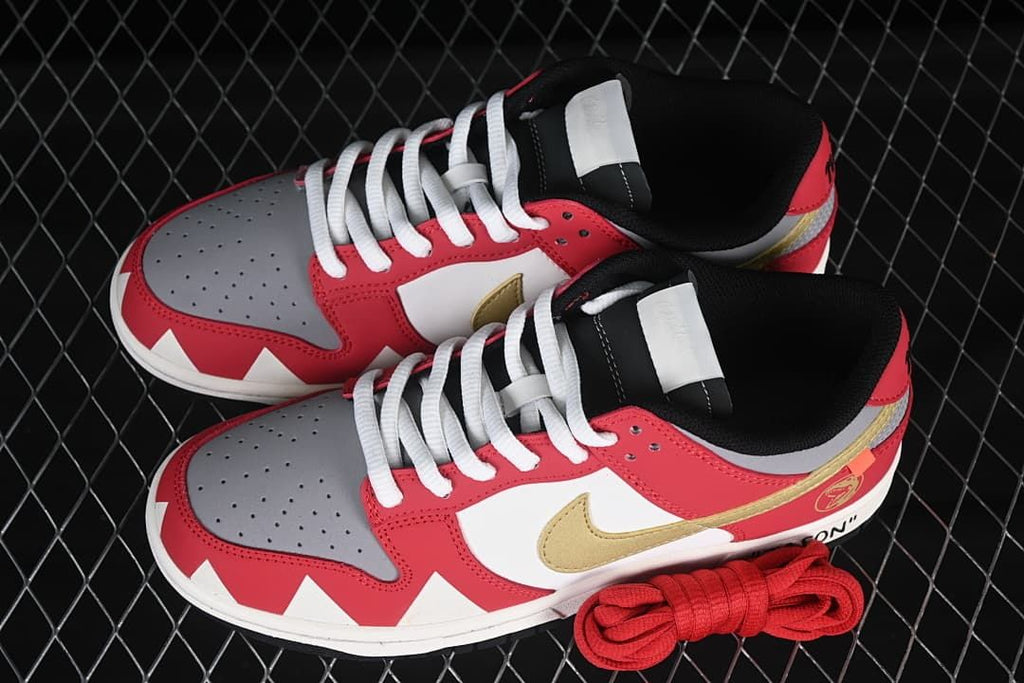Overhead view of the red, white, gray, and gold low-top sneakers with white laces and an extra pair of red laces.