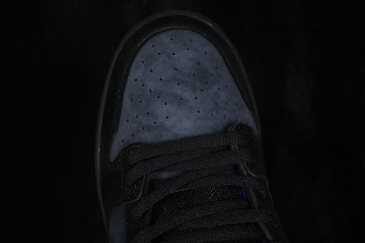 Close-up view of the perforated dark toe box and black laces on a Nike SB Dunk Low sneaker.