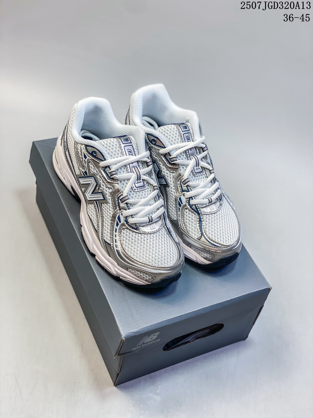Pair of silver, white, and navy New Balance 740 sneakers displayed on a shoebox.