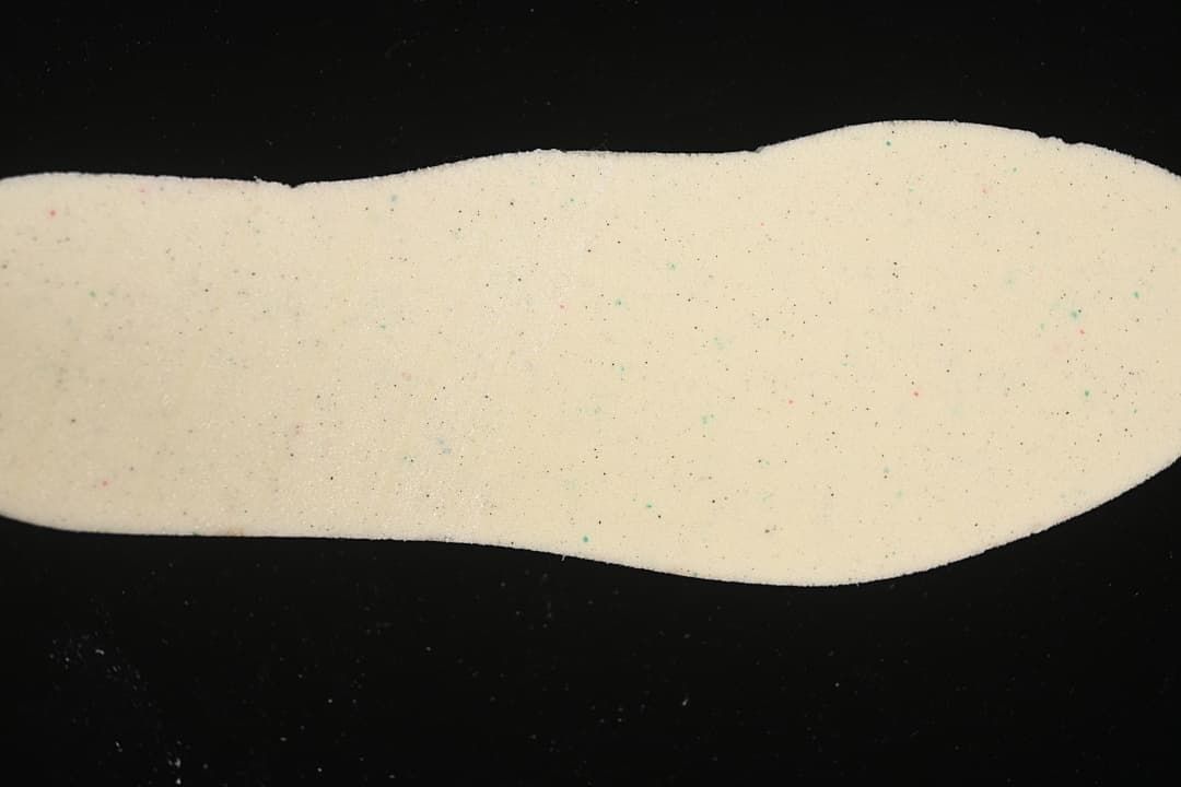 Light-colored shoe insert photographed on a black background