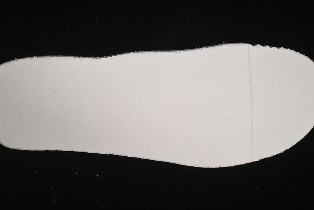 Plain light-colored insole shown against a dark background