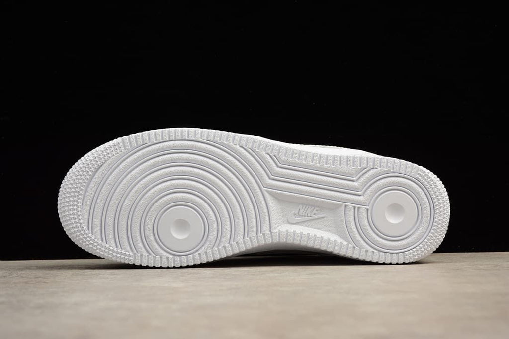 Underside of the white sneaker showing the circular outsole tread.