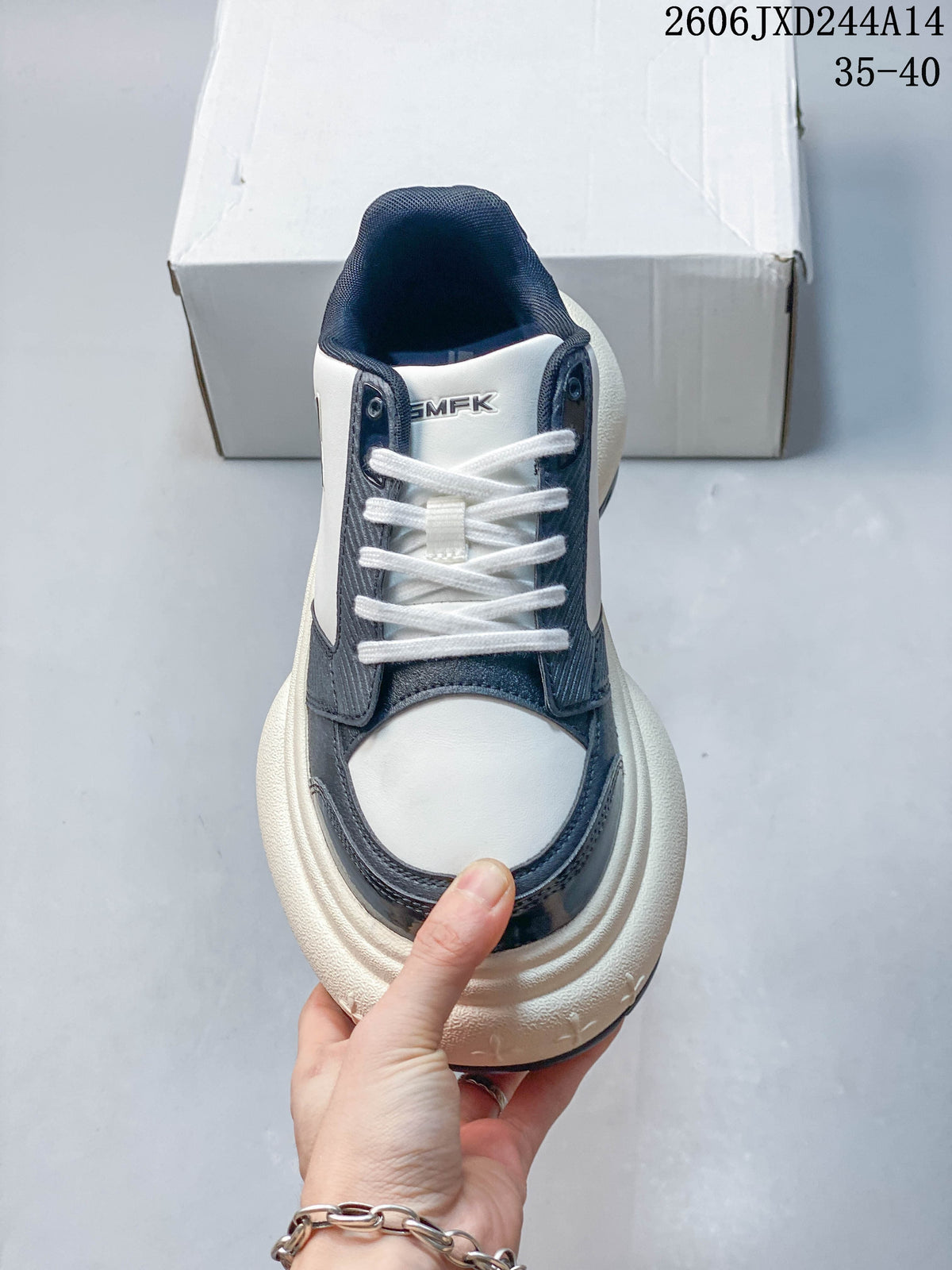 Front view of a white and navy SMFK sneaker with white laces