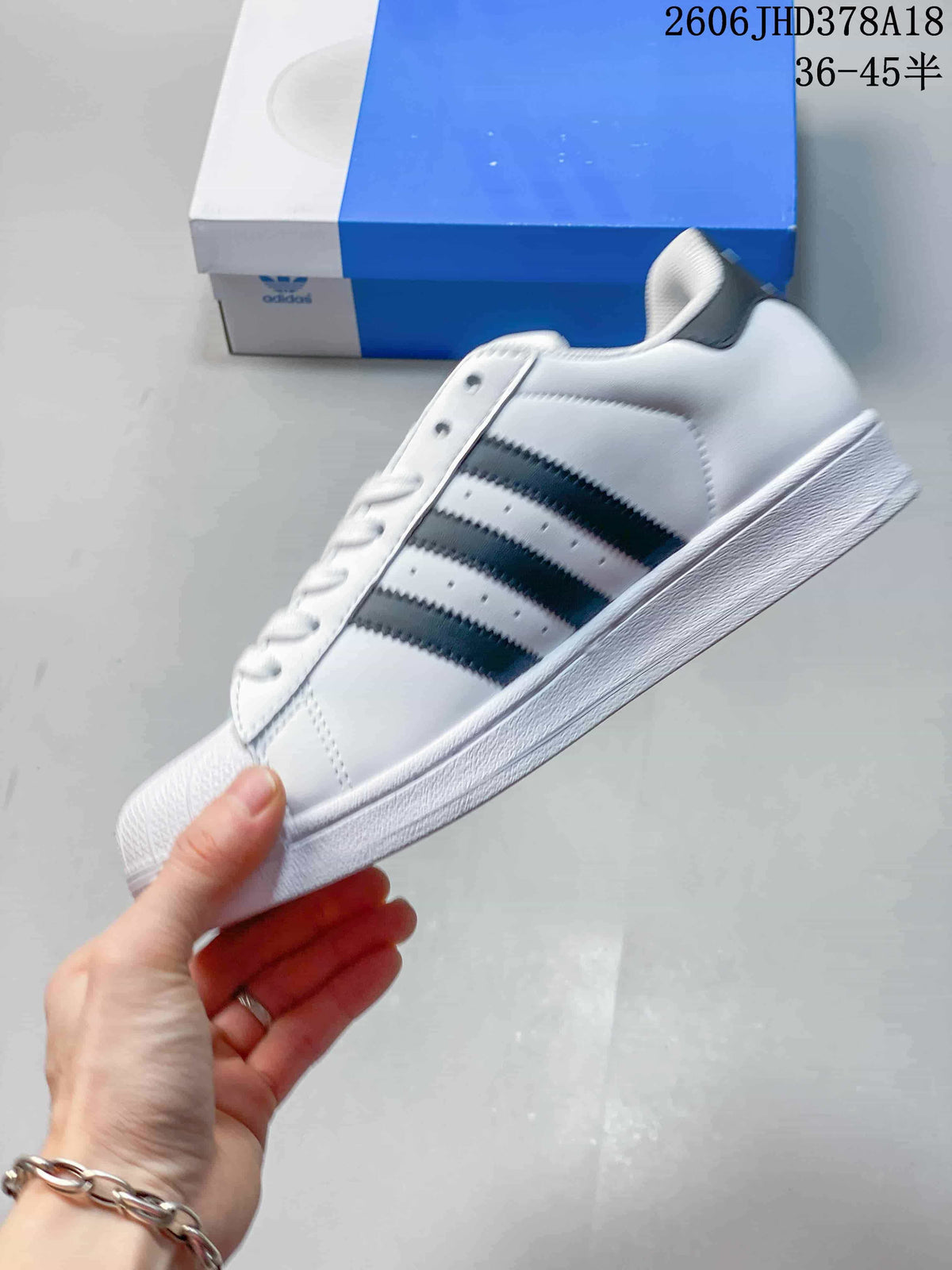 Side view of the white low-top sneaker with three black stripes