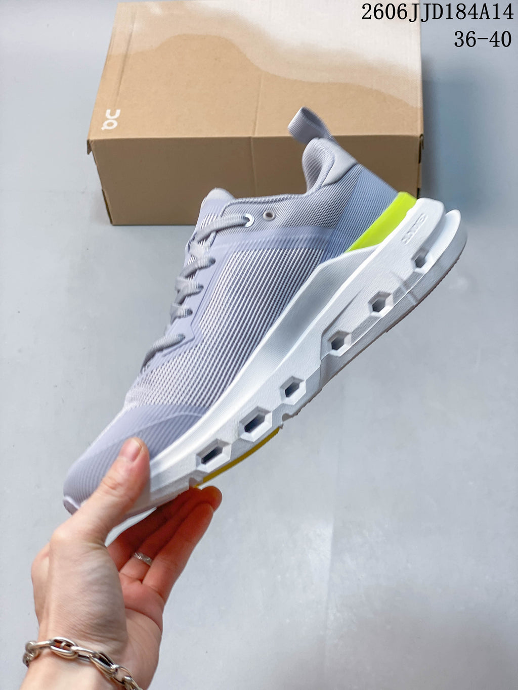 Side view of a grey On Cloudpulse Next shoe with a white geometric sole and yellow heel accent.