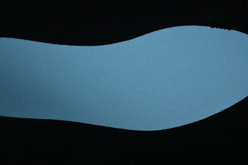 Separate blue insole component photographed against a dark background.