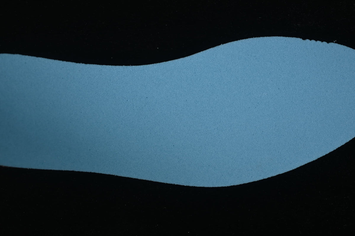 Separate blue insole component photographed against a dark background.