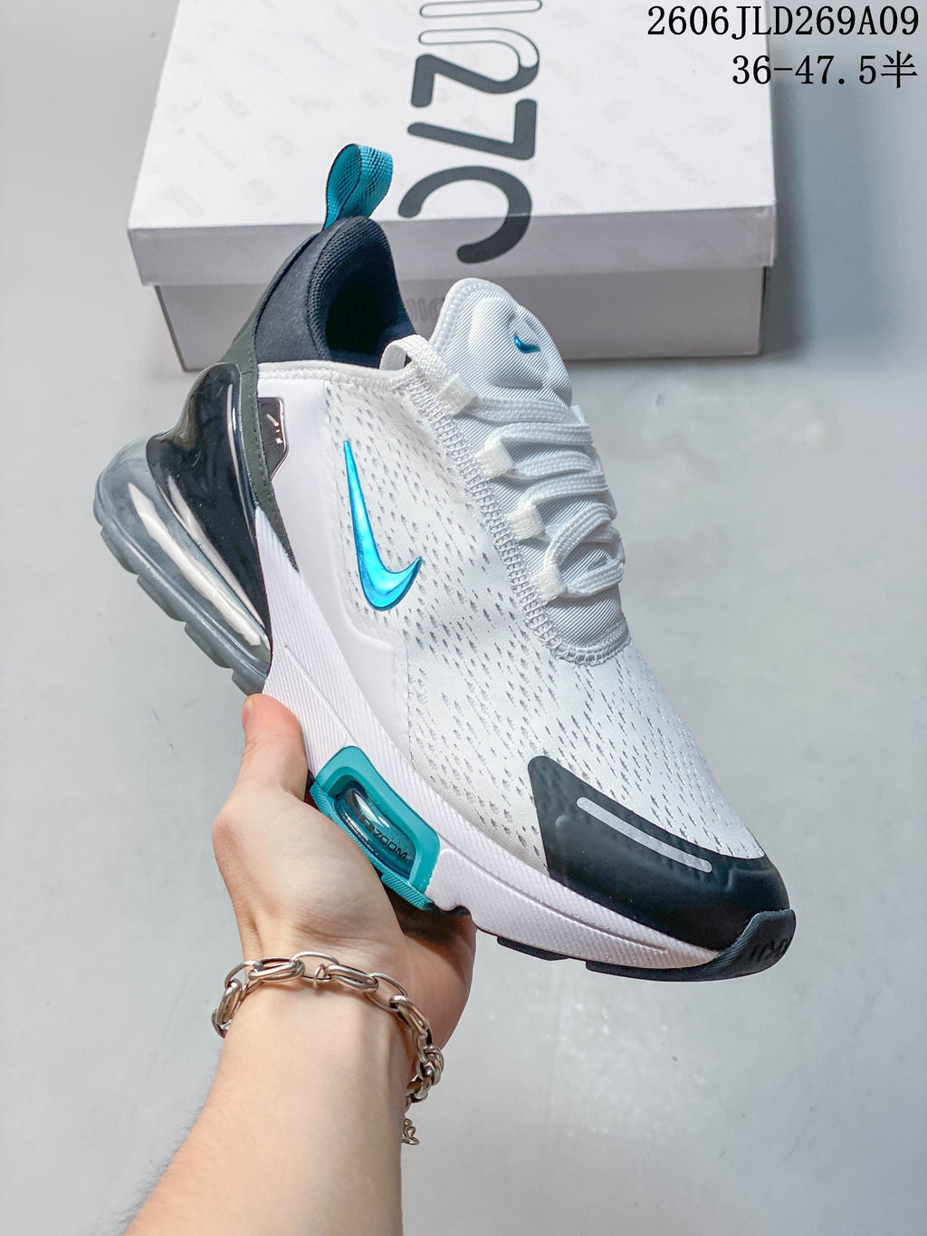 Side view of a white Nike Air Max 270 sneaker with teal branding and a visible heel unit