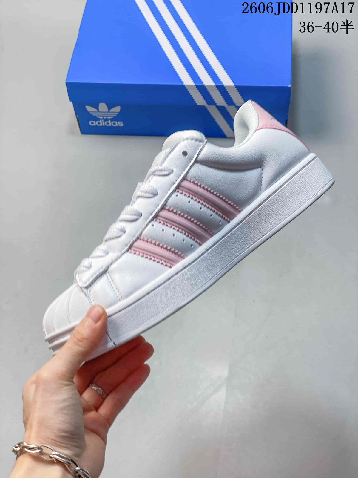 Side view of the white sneaker with pink stripes and a shell toe.
