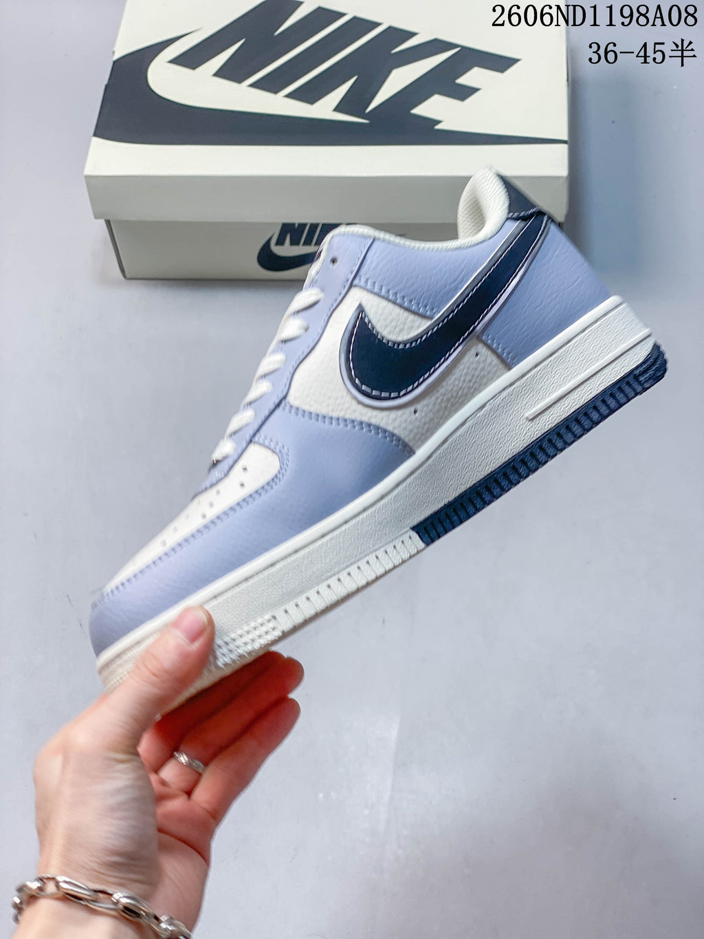 Side view of the light-blue and off-white low-top sneaker with a dark Swoosh panel, white midsole, and dark outsole; image overlay shows code 2606ND1198A08 and size range 36–45.5.
