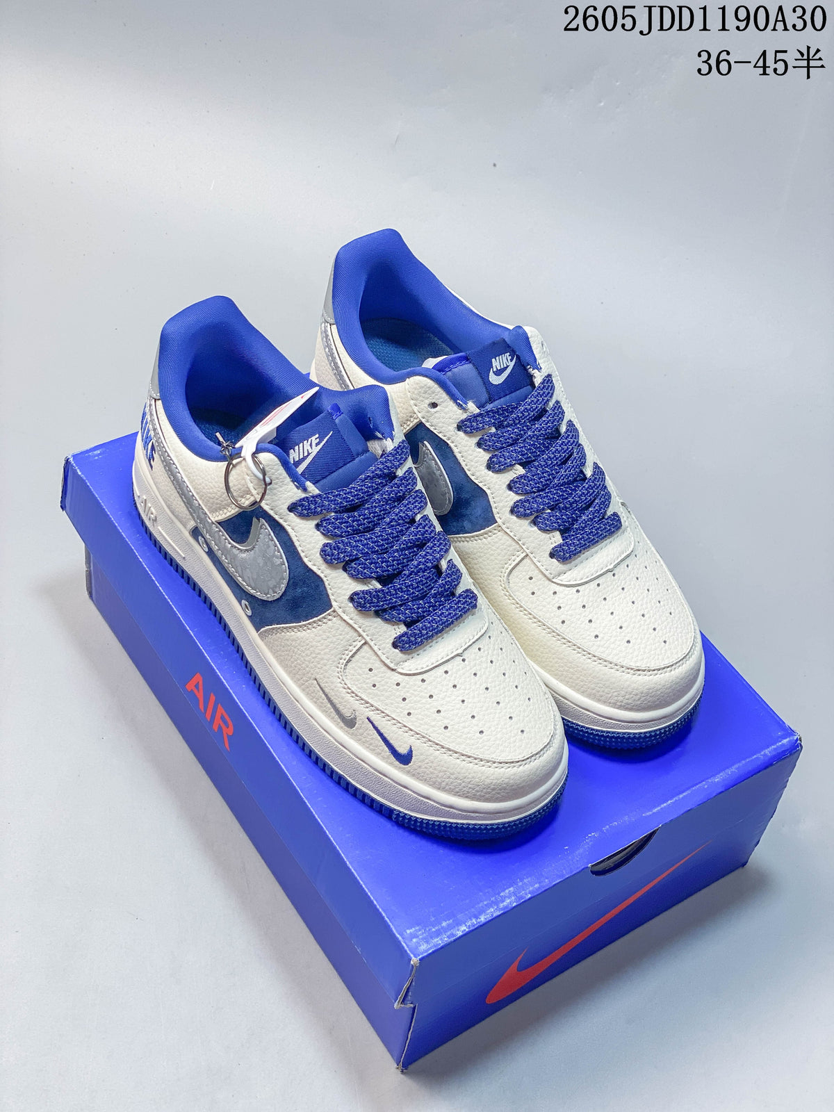 Pair of white low-top sneakers with blue panels, blue laces, and metallic-patterned swoosh details