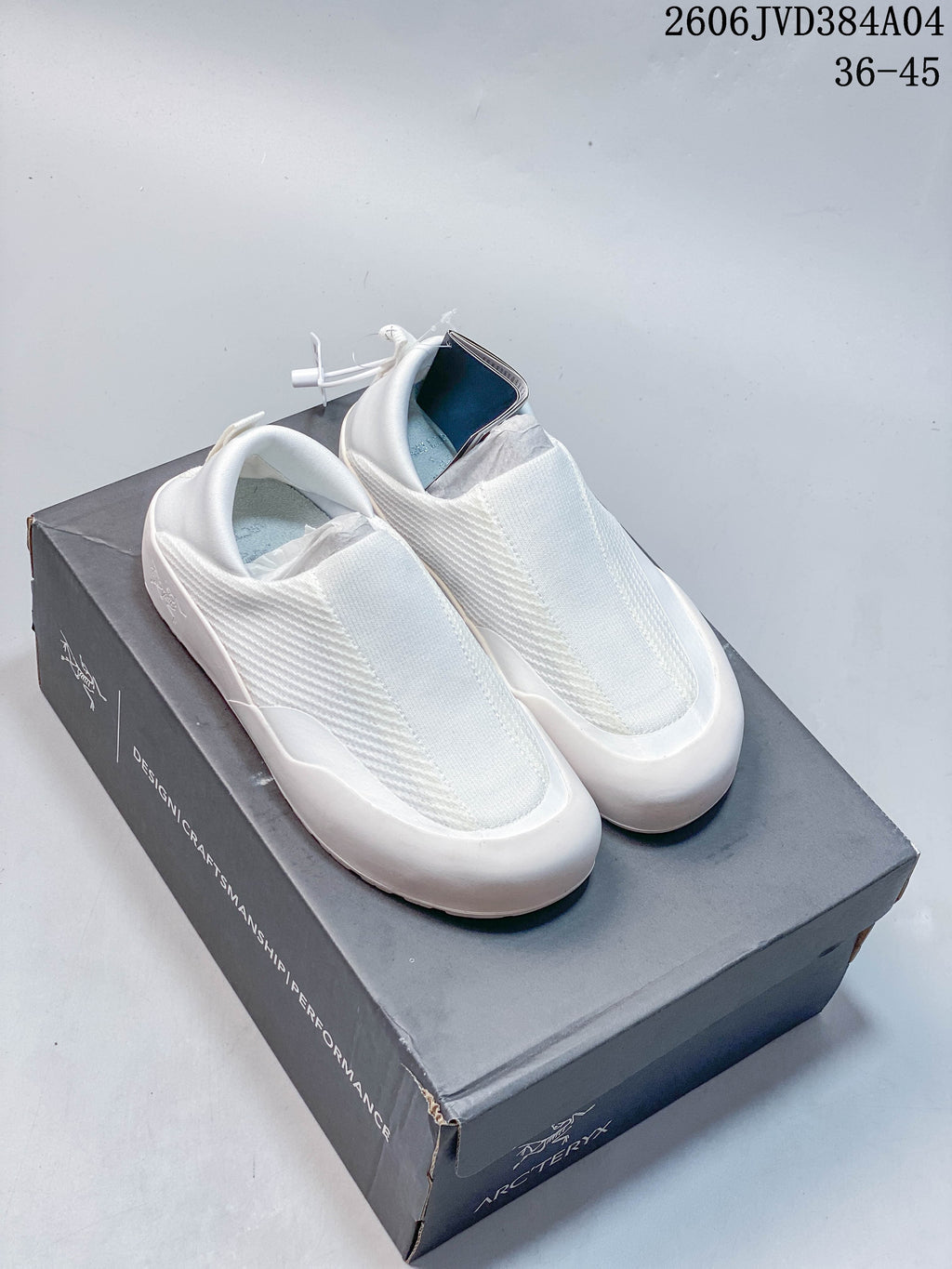 Pair of white Arc'teryx Kragg slip-on shoes displayed on a shoe box