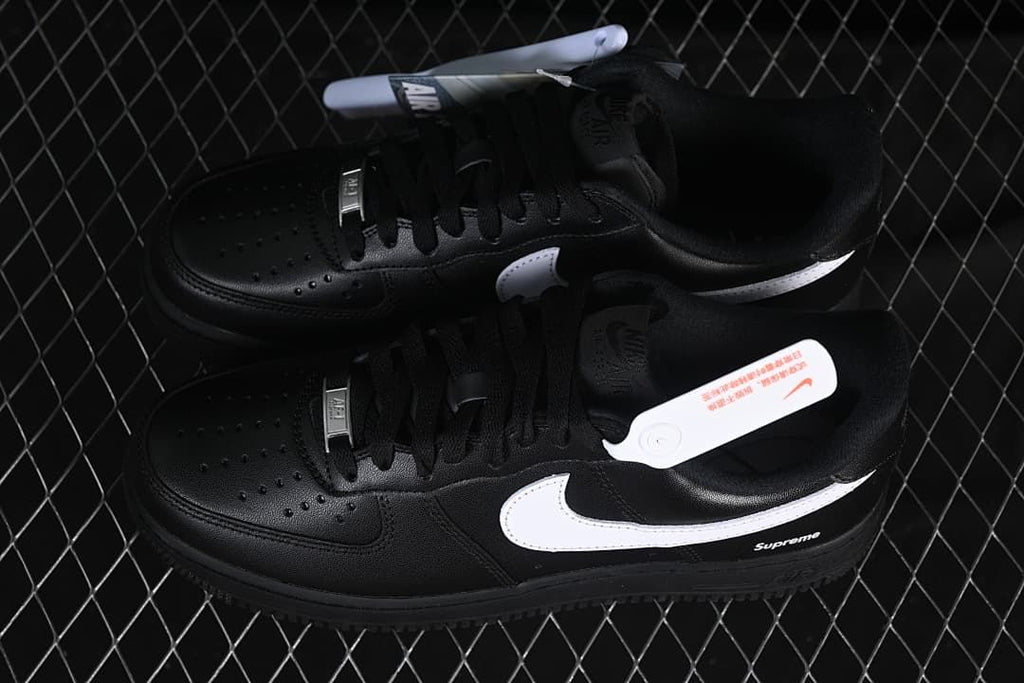 Pair of black low-top sneakers with white Swooshes and Supreme details